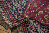 Folded antique Karabagh runner shows plum and navy fields with intricate floral and boteh designs.