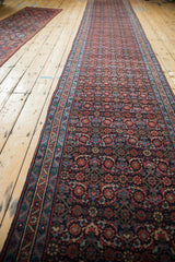 A long vintage Persian runner viewed from an angle, highlighting the repeating Herati design.
