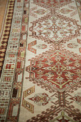Detail of distressed Serab rug runner's beige field, potted plants, and pawn border.