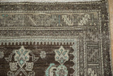 Corner of distressed Malayer runner, chocolate brown field, serrated leaf border, powder blue blossoms.