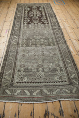 Distressed Malayer runner end, serrated border, fringe, and time-softened chocolate, platinum hues.