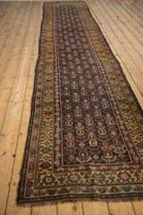 Angled perspective down the length of a vintage Qashqai runner with a bold saffron gold border.
