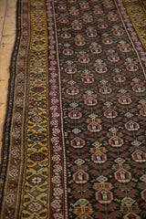Angled view of the saffron gold border and repeating plant motifs on a vintage Persian runner.