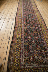 Angled view of a vintage Qashqai runner's repeating plant motif and saffron gold border design.