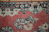 Distressed Persian Arak rug detail: faded cherry red field, navy, ivory, mint floral motifs.