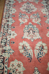 Faded cherry red ground of a vintage Arak rug, featuring ivory floral sprays and noticeable pile wear.