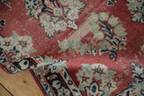 Distressed Arak runner's curled edge, showing faded cherry red floral field and blossom border.