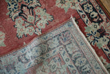 Distressed vintage Arak rug's faded cherry red pile and intricate hand-knotted foundation weave.