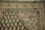 Distressed Malayer rug detail, showing abrashes in dusty teal, ivory, and patterned border.