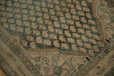 Textured close-up of vintage Malayer runner's distressed dusty teal boteh and serrated border.