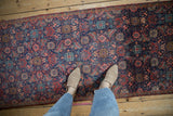 Vintage Persian Tabriz runner with royal blue Herati pattern and red motifs, shown with feet.