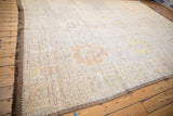 Distressed Oushak carpet showing original side selvage and faded palmette motifs.