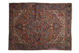 Vintage Heriz carpet with oversize geometric medallion, brick red, navy blue, and floral motifs.
