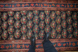 A view down the antique Persian runner showing staggered rows of floral bouquets.
