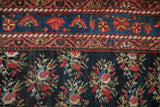 Detail of an antique Persian rug's sky blue floral border and navy field with rose bouquets.