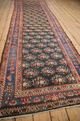 A long perspective of an antique Persian runner's staggered floral pattern and vibrant blue border.