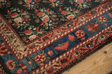 Corner of an antique Persian runner showing floral borders in blush, ruby, and sky blue.
