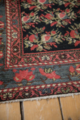 Corner of an antique Persian runner showing the intricate floral borders in ruby red and dusty teal.