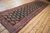 Antique Northwest Persian runner shown at full length, with repeating floral bouquets on a dark navy blue field.