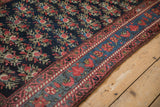 Detailed corner of an antique Persian runner with rose bouquets on navy and a ruby red and blue border.