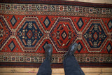 Overhead perspective of a vintage Persian Serab runner with interconnected hexagonal medallions in blue and red.