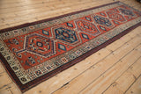Angled, full-length view of a vintage Serab runner with geometric red and blue medallions.