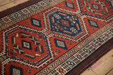 Angled view of interconnected sapphire blue and brick red medallions on a vintage Persian runner.