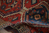 A fold in a vintage Serab rug highlights its intricate geometric pile in brick red and sapphire blue.