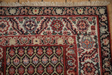 Corner detail of vintage Malayer runner with antique ivory fringe, chocolate brown, and red borders.