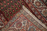 Folded vintage Malayer rug corner, intricate hand-knotted foundation, floral motifs, and fringe.