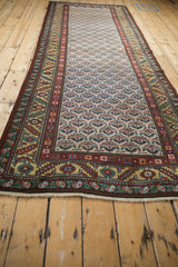 Corner of a vintage runner showing the gold-ground serrated leaf border and clean ivory fringe.