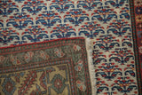 Folded corner of a Persian runner reveals the hand-knotted foundation and gold-toned border.