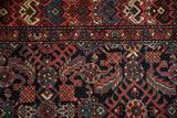 Close view of the hand-knotted Herati design and floral border in navy, red, and teal.