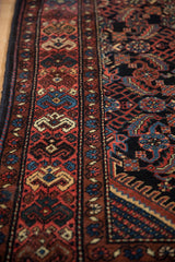 Intricate geometric main border in brick red and dusty teal on a hand-knotted Persian runner.
