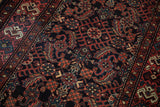 Angled view of the vintage Hamadan rug's Herati pattern with brick red and dusty teal details on a navy field.