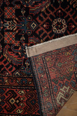 A corner of a vintage Hamadan rug folded back to reveal the dense, hand-knotted construction.
