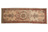 Antique Karabagh runner with a large tiered palmette medallion on a sand and ivory field with deep red borders.