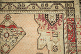 Distressed low pile texture on an antique Karabagh rug corner with geometric madder red motifs.