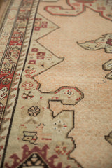 Evenly worn pile on an antique Karabagh rug showing geometric border details in beige, red, and charcoal.