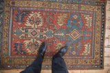 A view from above showing the vintage Heriz rug's texture and geometric design in red and blue.