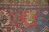 A unique finned-tail bird motif beside the starburst border of a vintage Heriz rug.