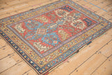 Angled view of a vintage Heriz rug with a geometric medallion and starburst blossom border.