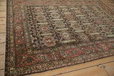 Distressed Hamadan rug corner, showing finned blossoms, boteh border, and softened red hues.