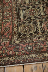 Distressed Hamadan rug corner, showcasing madder red boteh border and textured field.