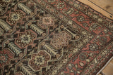 Detail of the distressed Hamadan rug showing charcoal field, finned blossoms, and madder red boteh border.
