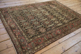 Distressed Hamadan rug corner, showcasing madder red border's unique boteh motif.