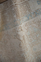 Folded vintage Karaja rug runner showing distressed pile and muted beige, pale blue patterns.