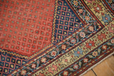 Antique Northwest Persian runner corner: ruby red field, sapphire blue geometric border, and fringe.