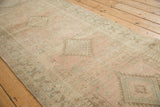 The low-pile texture and repeating geometric medallions of a distressed vintage Serab runner.