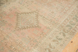 Worn pile of a vintage Serab runner showing a serrated medallion in blush, beige, and jade.